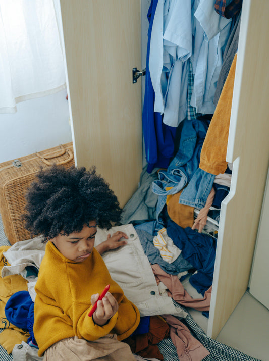 A kid sorts through kids clothing to form a toddler capsule wardrobe